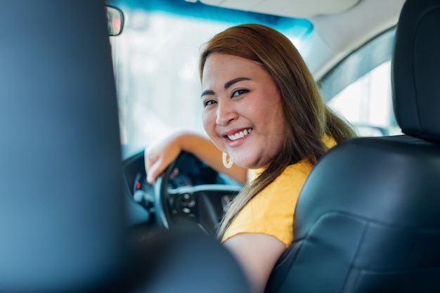 bella giovane donna asiatica sorridente felice che guida la sua macchina nuova?