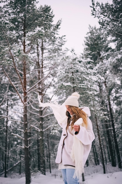 Bella giovane donna attiva in vestiti bianchi che gode della foresta di inverno nevoso