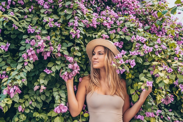 Bella giovane donna bionda che posa con i fiori tropicali