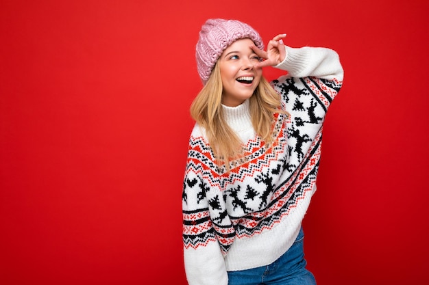 Bella giovane donna bionda felice positiva isolata sopra la parete variopinta del fondo che indossa vestiti alla moda casuali che provano emozioni sincere che guardano al lato.