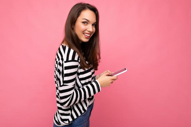 Bella giovane donna bruna che utilizza il telefono cellulare comunicando tramite messaggi di testo indossando un maglione