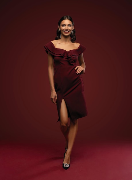 Bella giovane donna bruna con un'acconciatura elegante Donna con trucco da sera in abito rosso e scarpe col tacco alto