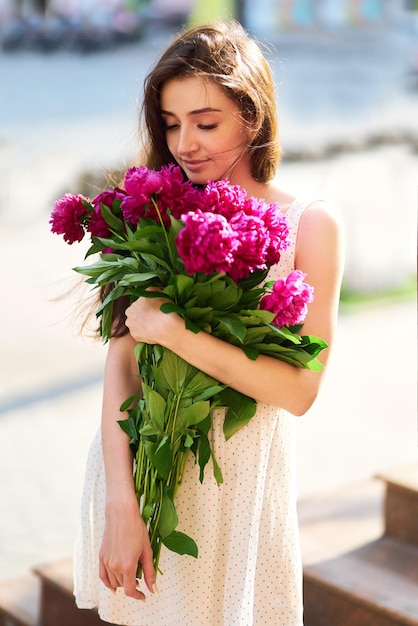 Bella Giovane Donna Bruna In Un Bel Vestito Di Primavera Con Un Mazzo Di Pioni