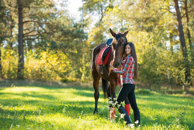 Bella giovane donna capelli lunghi in posa con un cavallo all'aperto