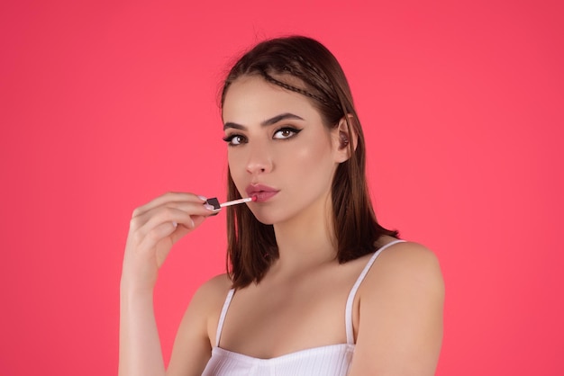 Bella giovane donna che applica rossetto rosso sulle labbra studio colore sfondo ragazza sexy applicata