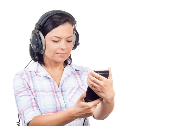 Bella giovane donna che ascolta musica con cuffie e telefono cellulare su sfondo bianco