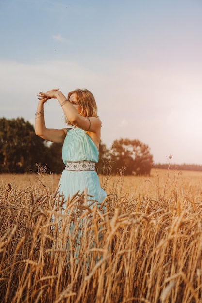 Bella giovane donna che balla nel campo al tramonto