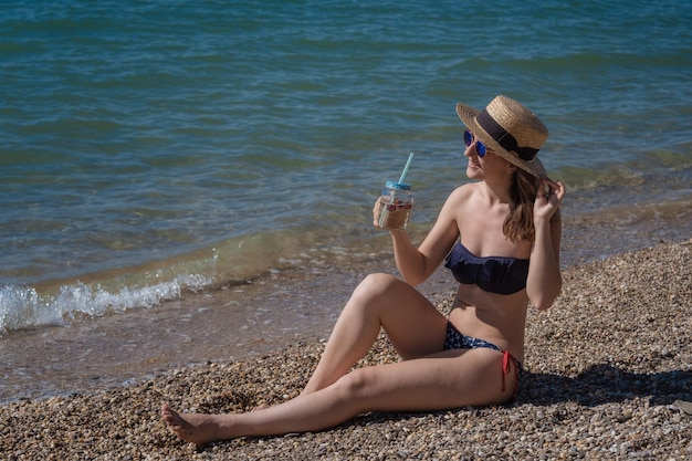 Bella giovane donna che beve cocktail sulla spiaggia Ragazza attraente che offre un drink Bella donna che beve limonata