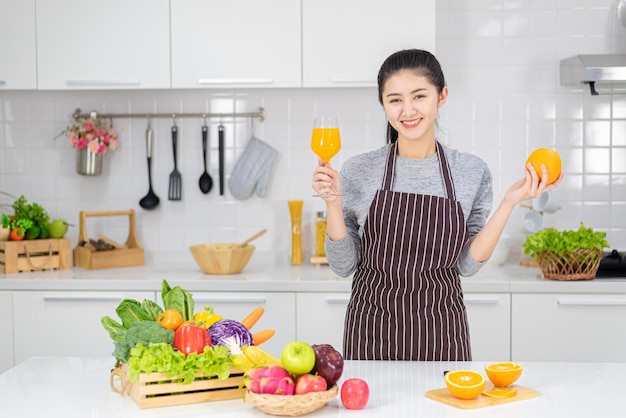 Bella giovane donna che beve succo d'arancia fresco in cucina. Dieta sana