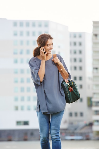 Bella giovane donna che cammina e parla al cellulare