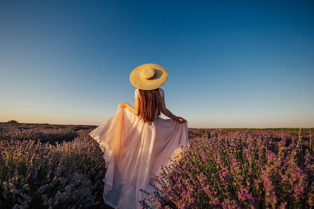 Bella giovane donna che cammina il campo di lavanda in Provenza, Francia.