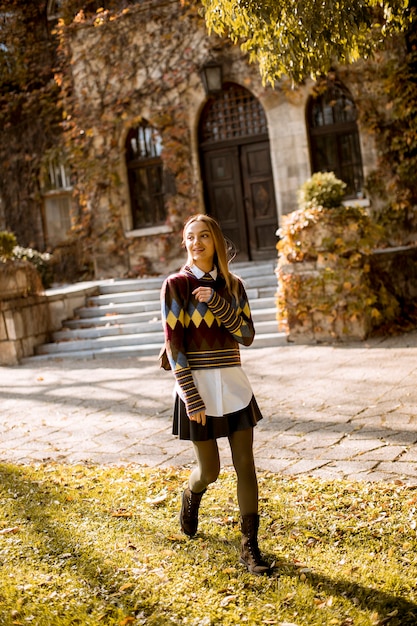 Bella giovane donna che cammina nel parco in autunno in una giornata di sole