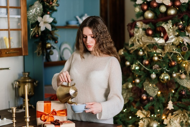 Bella giovane donna che celebra il natale a casa, divertendosi mentre apre i regali