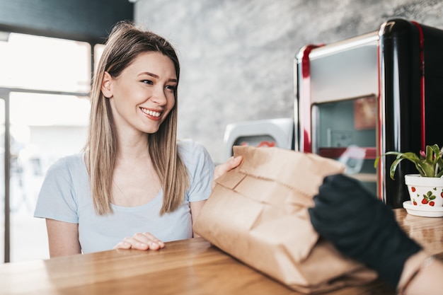 Bella giovane donna che compra cibo in un ristorante fast food.