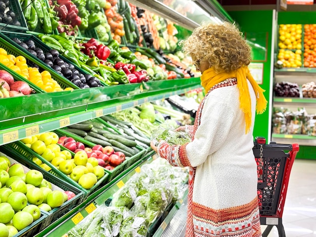 Bella giovane donna che compra frutta e verdura nel reparto dei prodotti alimentari di un supermercato immagine colorata