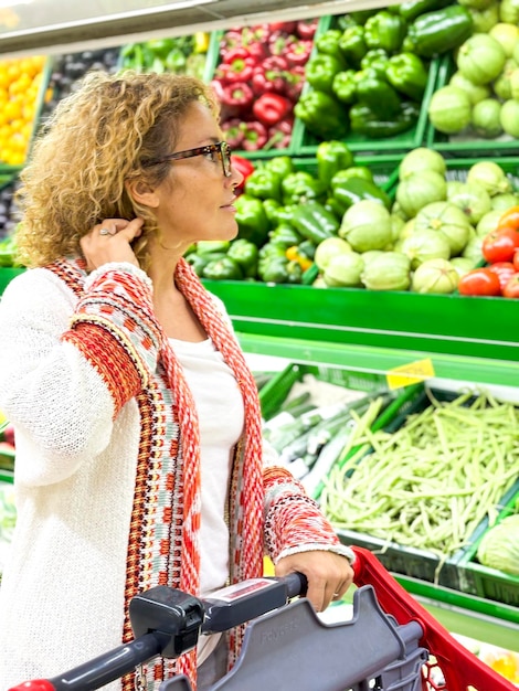 Bella giovane donna che compra frutta e verdura nel reparto dei prodotti alimentari di un supermercato immagine colorata