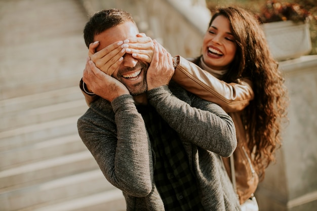 Bella giovane donna che copre gli occhi del suo ragazzo nel parco