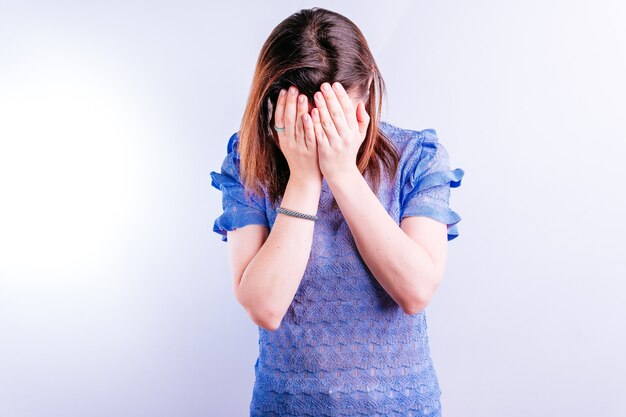 Bella giovane donna che copre il viso in simbolo di tristezza