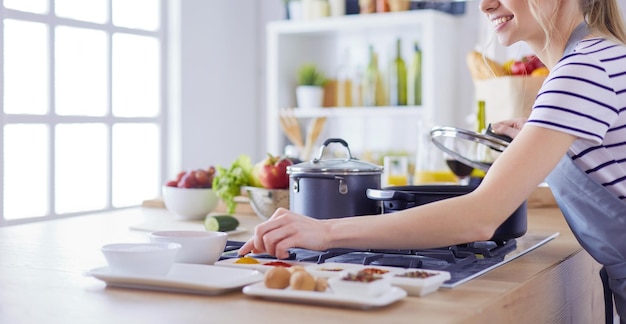 Bella giovane donna che cucina in cucina a casa