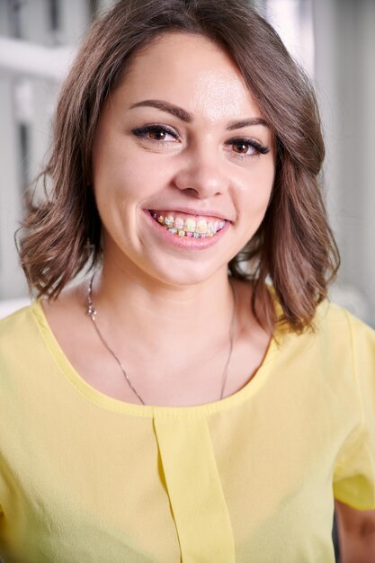 Bella giovane donna che dimostra i denti con le parentesi graffe