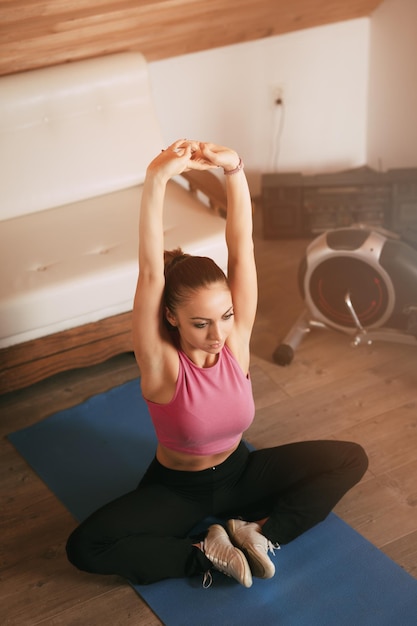 Bella giovane donna che fa esercizi di stretching a casa.