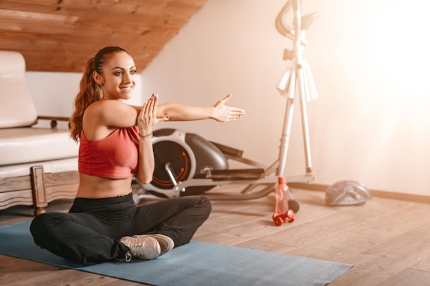 Bella giovane donna che fa esercizi di stretching a casa.