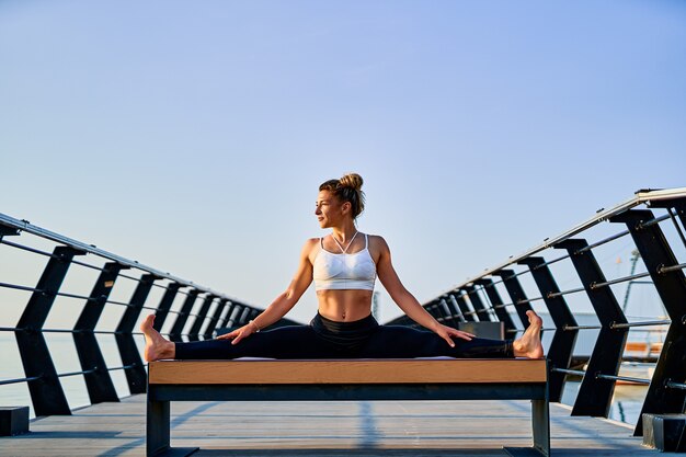 Bella giovane donna che fa esercizio di yoga sulla natura al mattino