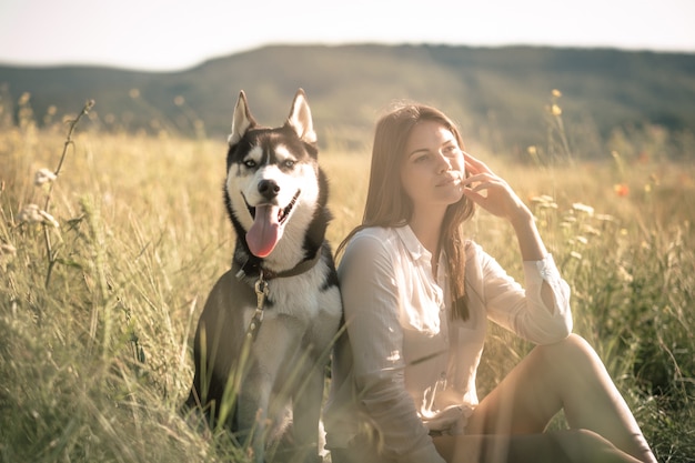 Bella giovane donna che gioca con il cane husky divertente all'aperto al parco