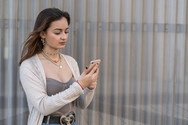 Bella giovane donna che guarda un messaggio sul suo smartphone