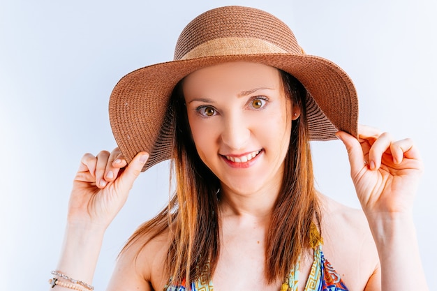 Bella giovane donna che indossa abiti estivi, cappello su sfondo bianco con spazio copia stringendo cappello da spiaggia. concetto di moda estiva da spiaggia