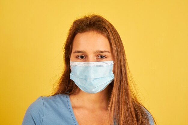 Bella giovane donna che indossa la maschera per il viso per prevenire l'infezione da coronavirus