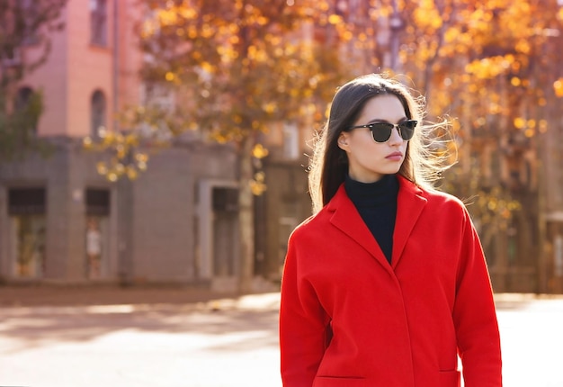 Bella giovane donna che indossa occhiali da sole il giorno d'autunno