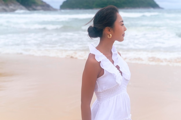 Bella giovane donna che indossa un abito bianco sulla spiaggia