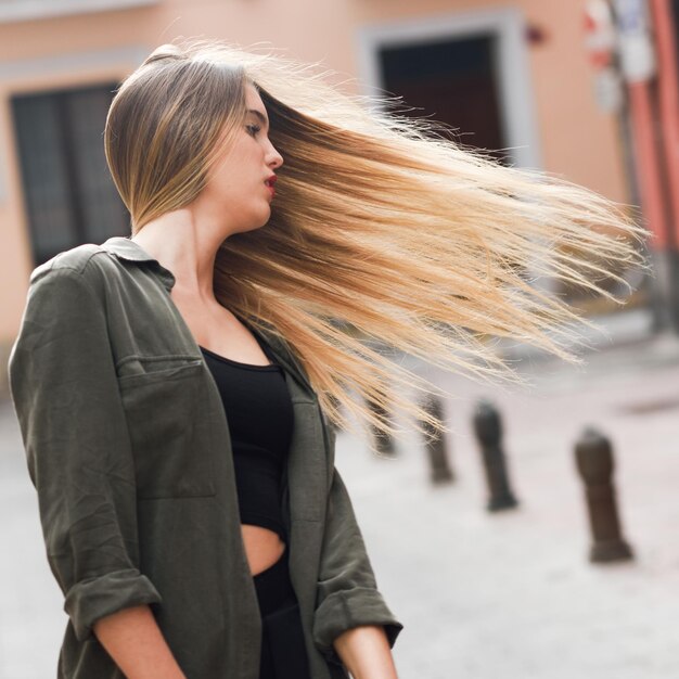 Bella giovane donna che lancia i capelli sul marciapiede