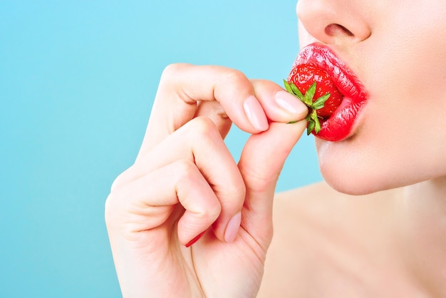 Bella giovane donna che mangia le fragole. L'immagine illustra dieta, cibo sano, bacche e frutti.