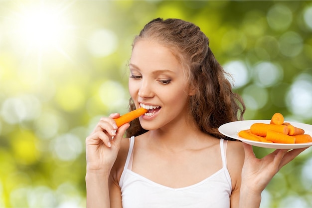 Bella giovane donna che mangia una carota