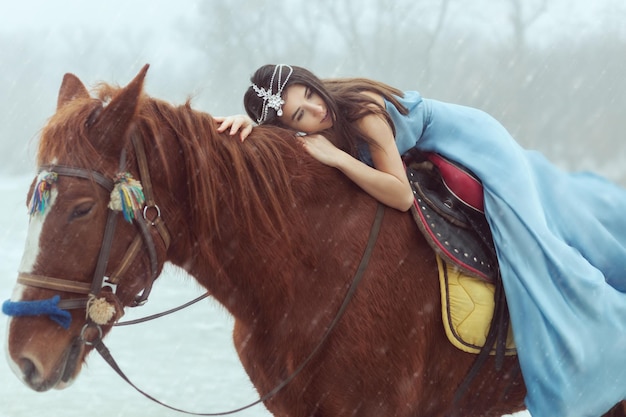 Bella giovane donna che monta un cavallo Sta nevicando