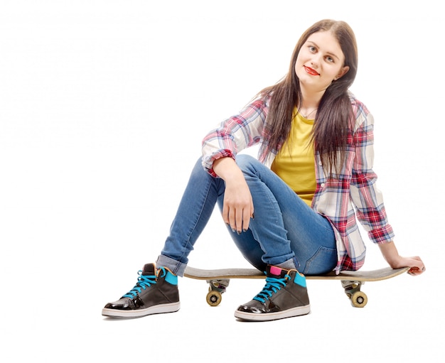 Bella giovane donna che posa con uno skateboard, sedile su skate