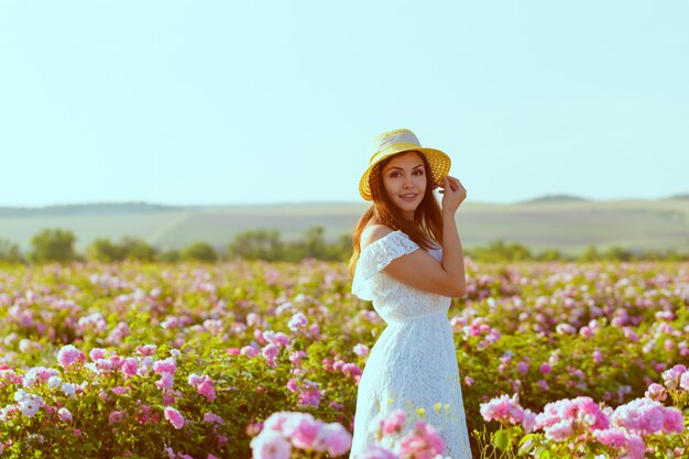 Bella giovane donna che posa vicino alle rose in un giardino.