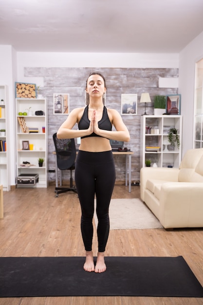 Bella giovane donna che pratica yoga per il suo benessere in soggiorno.
