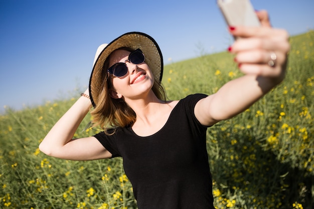 Bella giovane donna che prende un selfie in un campo.