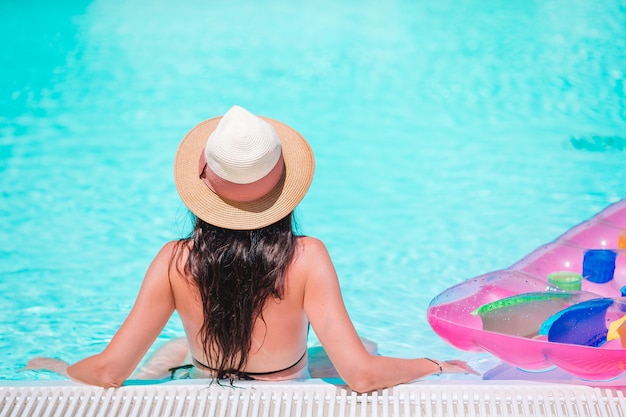 Bella giovane donna che si distende nella piscina.