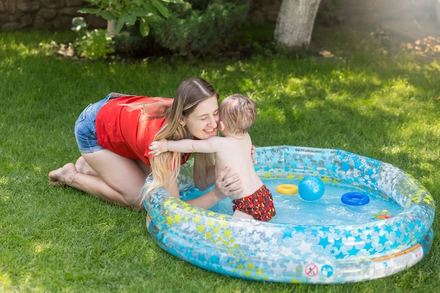 Bella giovane donna che si diverte con il suo bambino in piscina