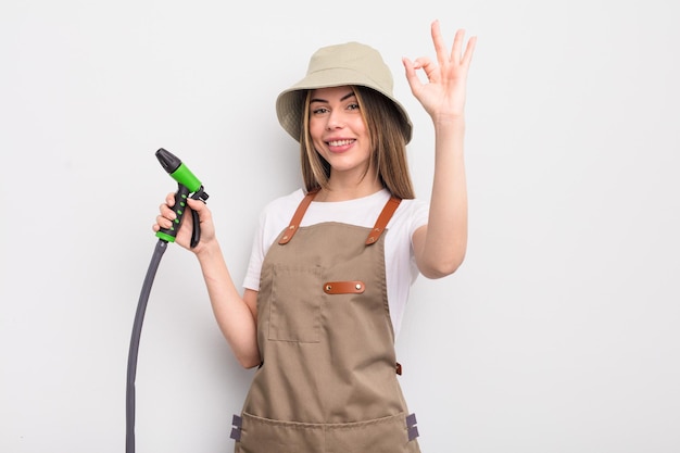 Bella giovane donna che si sente felice, mostrando approvazione con un gesto ok. concetto di irrigazione del giardiniere