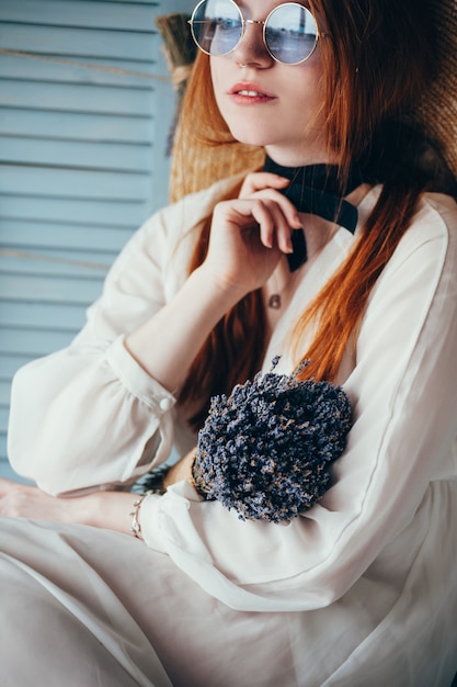 Bella giovane donna che si siede con la lavanda contro la parete blu.