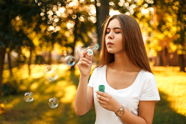 Bella giovane donna che soffia bolle di sapone