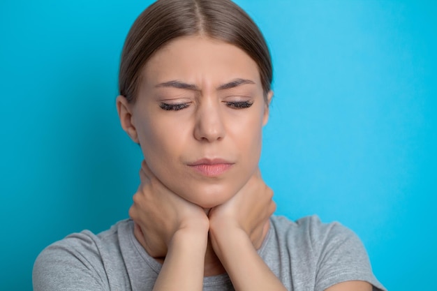 Bella giovane donna che soffre di dolore al collo