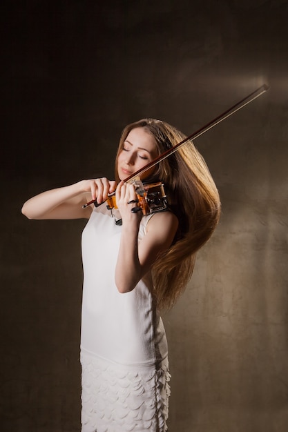 Bella giovane donna che suona il violino su sfondo nero