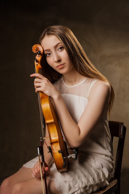 Bella giovane donna che suona il violino su sfondo nero