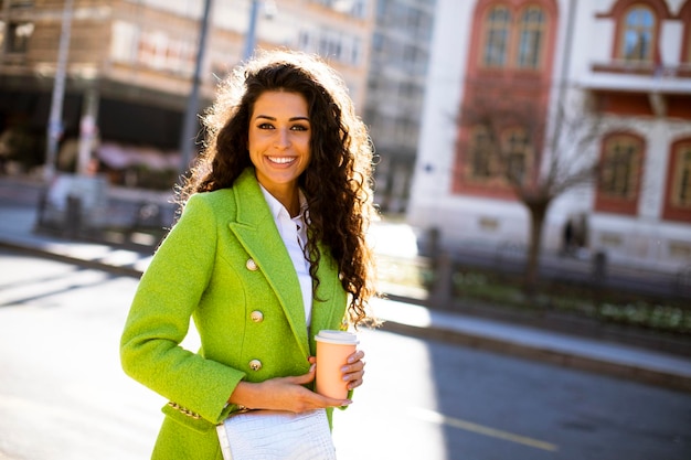 Bella giovane donna che tiene caffè da asporto per strada?